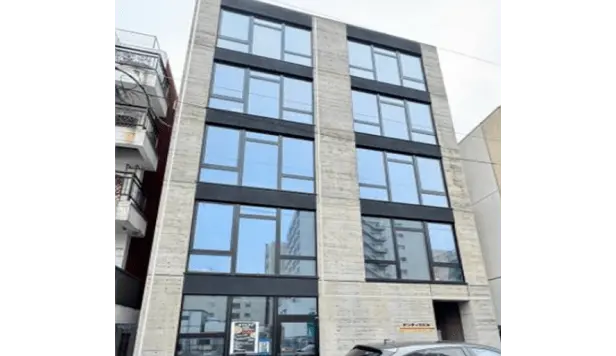グレーの打ちっぱなしコンクリートと大きなガラス窓が特徴の5階建てデザイナーズマンション。
                                                                