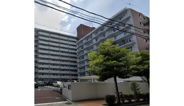 白いバルコニーが整然と並ぶ大型集合住宅。敷地内に緑が多く、整備された駐車スペースも完備