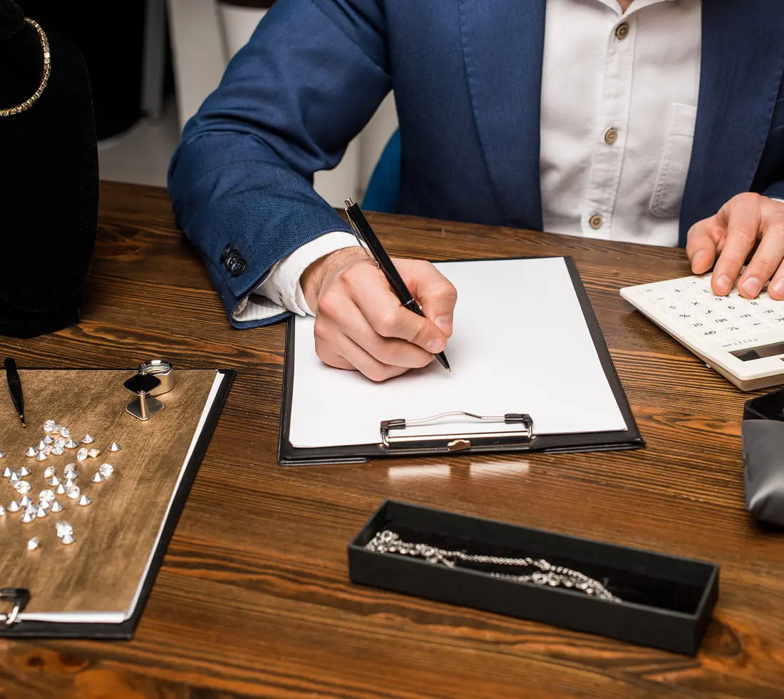 宝石ルーペや電卓が置かれた机の上で、査定中のシーン