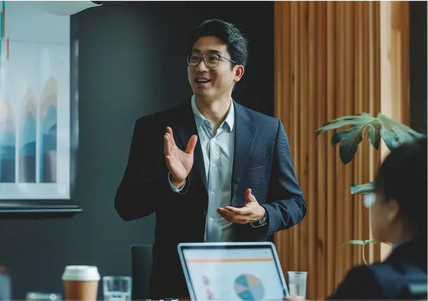 スーツ姿の男性が会議室でプレゼンテーションを行っている様子