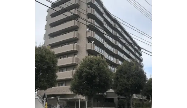 白と赤の縦ラインが特徴的な高層マンション。外壁工事中で、足場が建物の両側に組まれている。